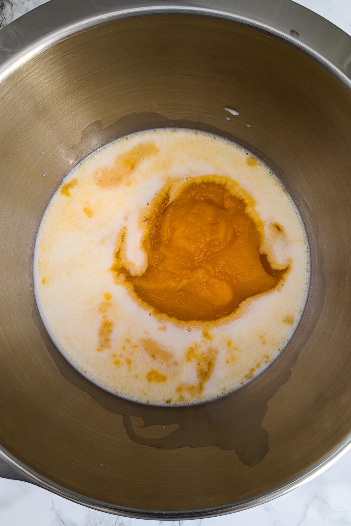 A mixture of pumpkin puree and milk in a metal pan.