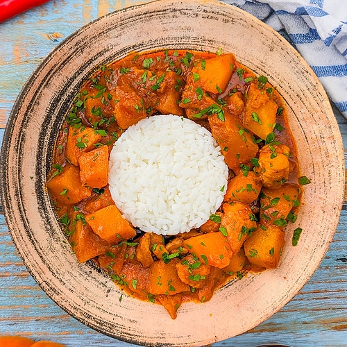 Pumpkin curry with rice and parsley in a vintage plate.