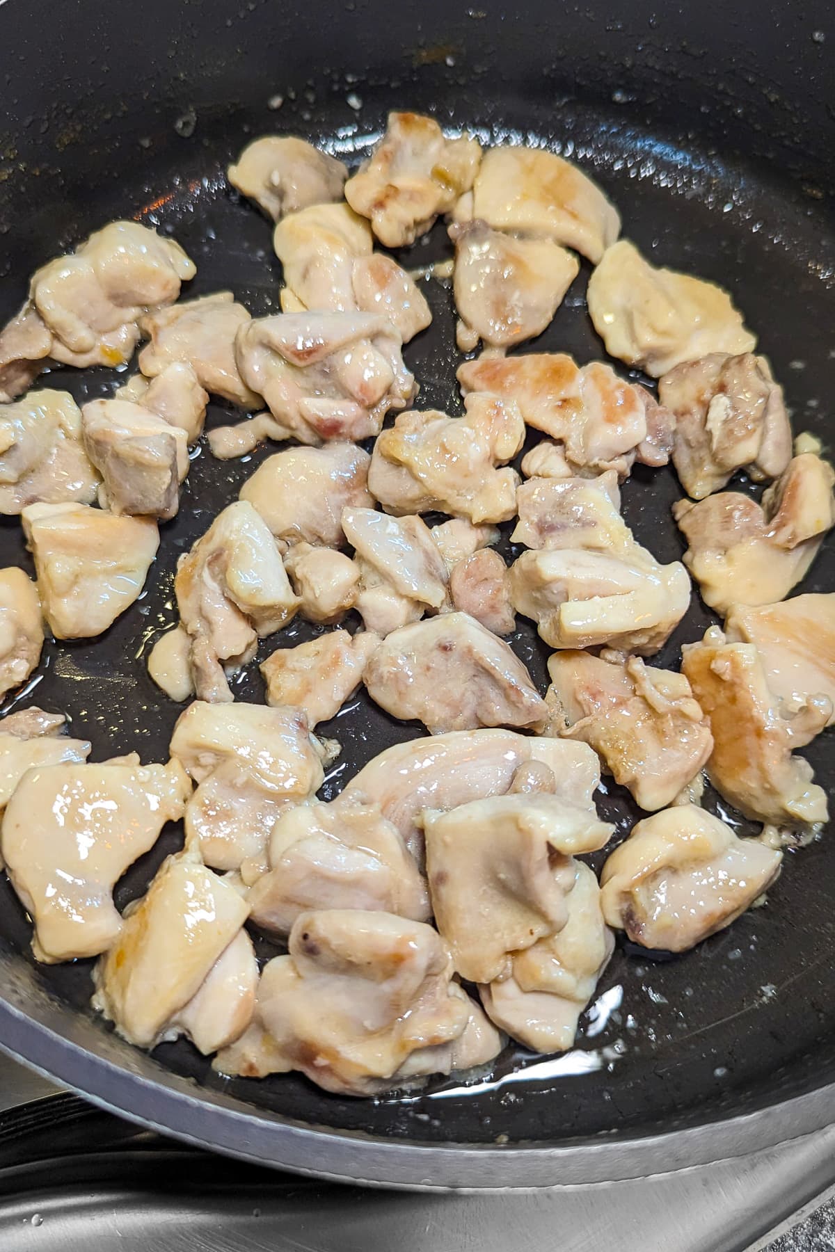Frying chicken in a pan on the stove.