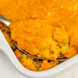 A spoon with pumpkin rice pudding in a white casserole.