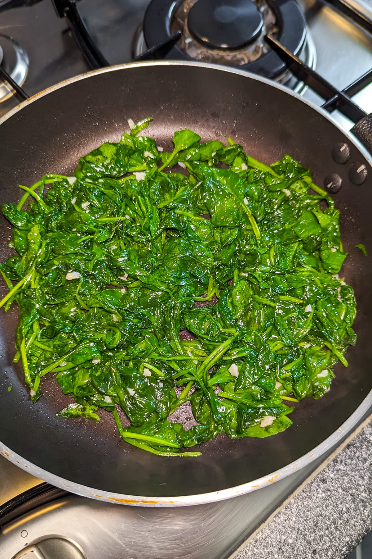 Cooked spinach in a frying pan on the stove.