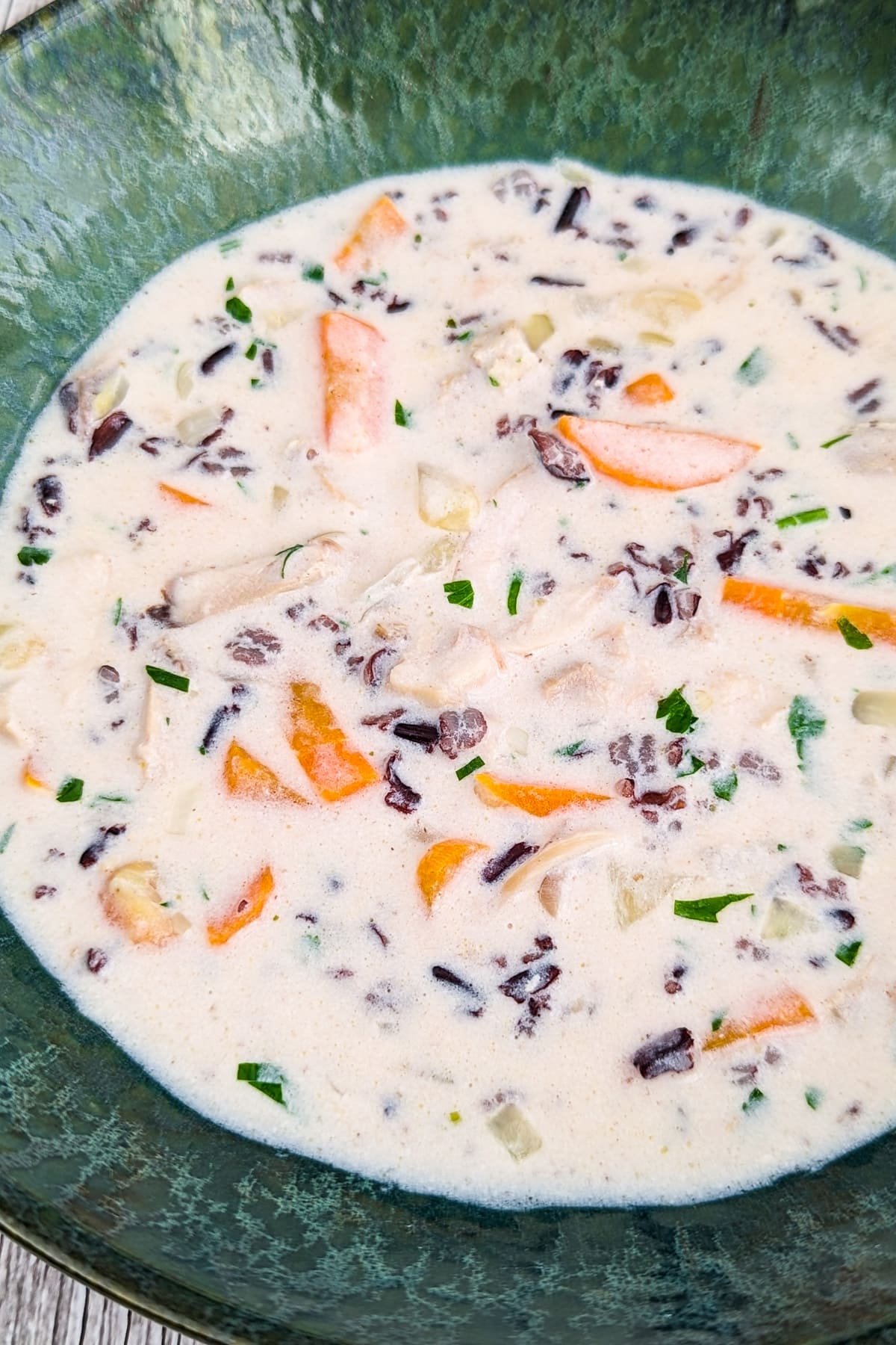 Wild rice soup with carrot and cream in a vintage green plate.