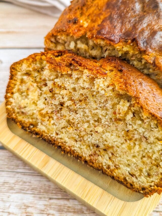 Close look of a slice of banana bread served on a wooden board.