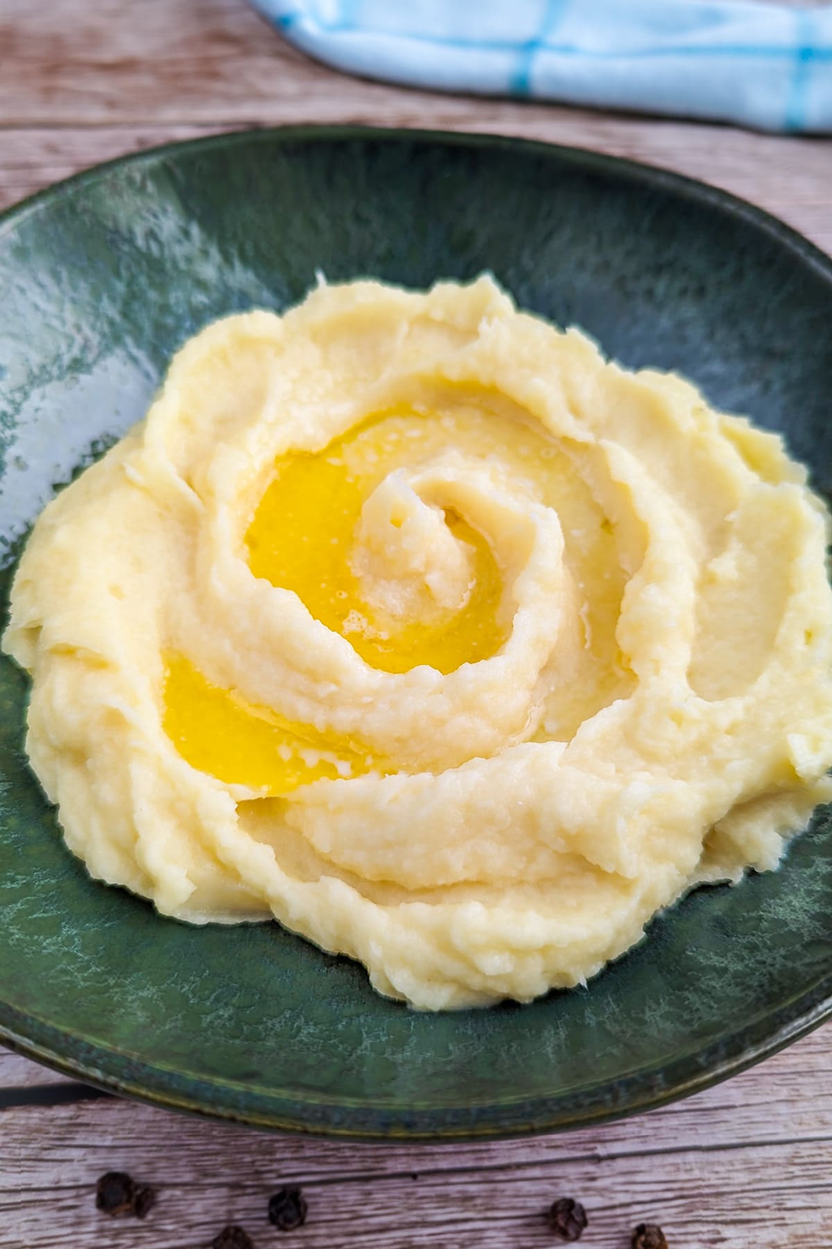 Mashed parsnips puree with melted butter on a green vintage plate.