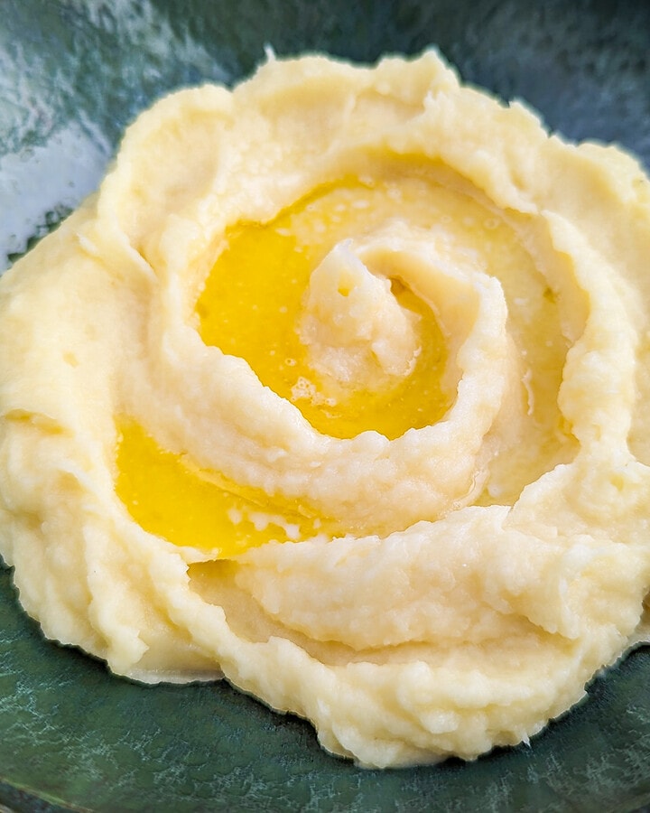 Mashed parsnips puree with melted butter on a green vintage plate.