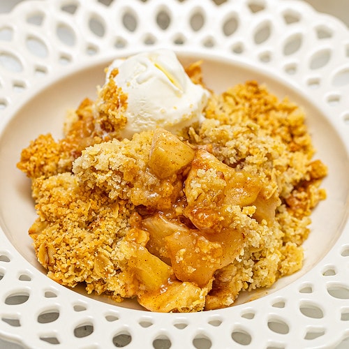 Close look of elegant vintage plate with apple crumble with a scoop of ice cream.