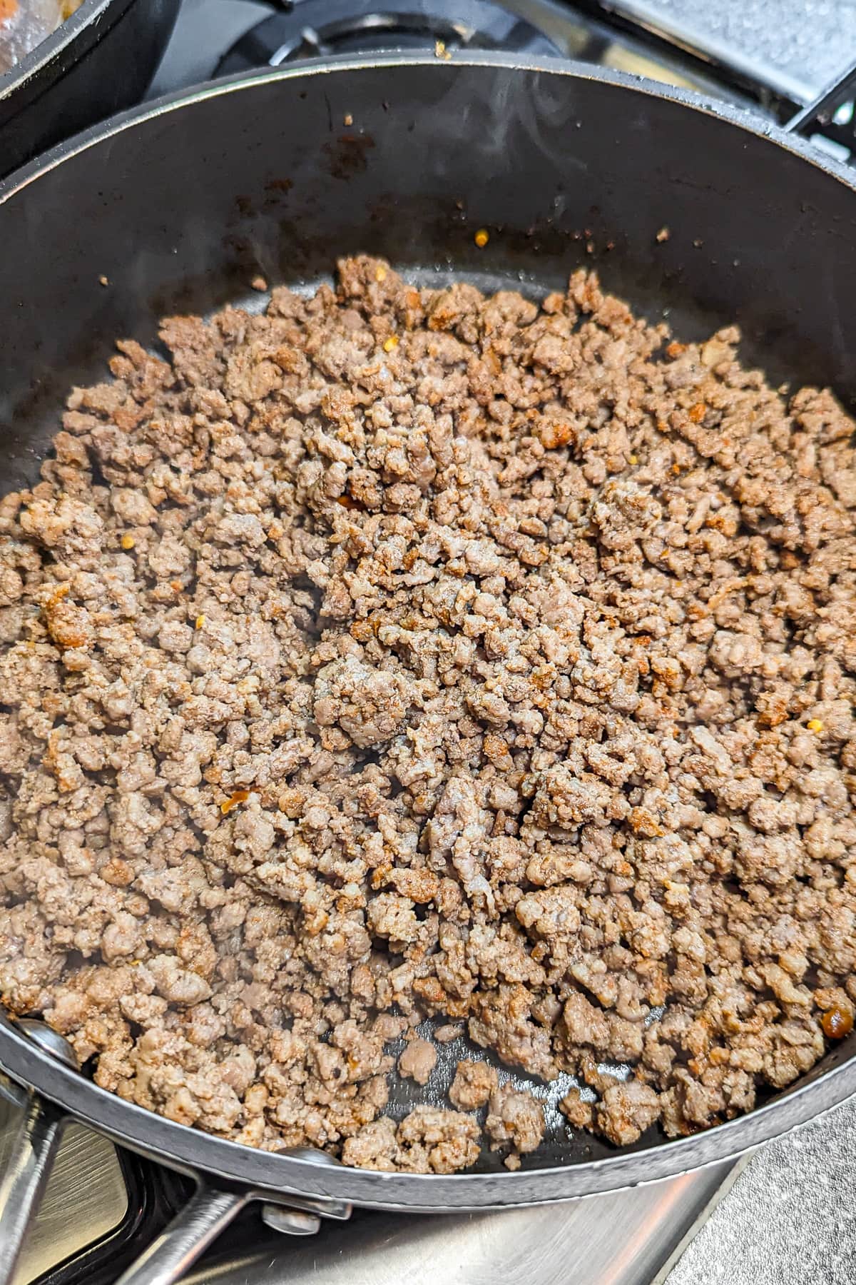Frying ground beef in a pan on the stove.