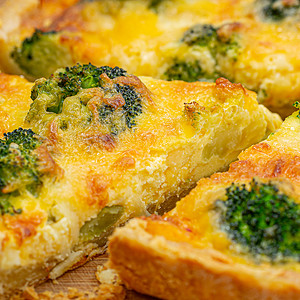 A close-up of a slice of broccoli cheddar quiche with a focus on the flaky crust, creamy filling, and vibrant broccoli, indicating a crispy texture.