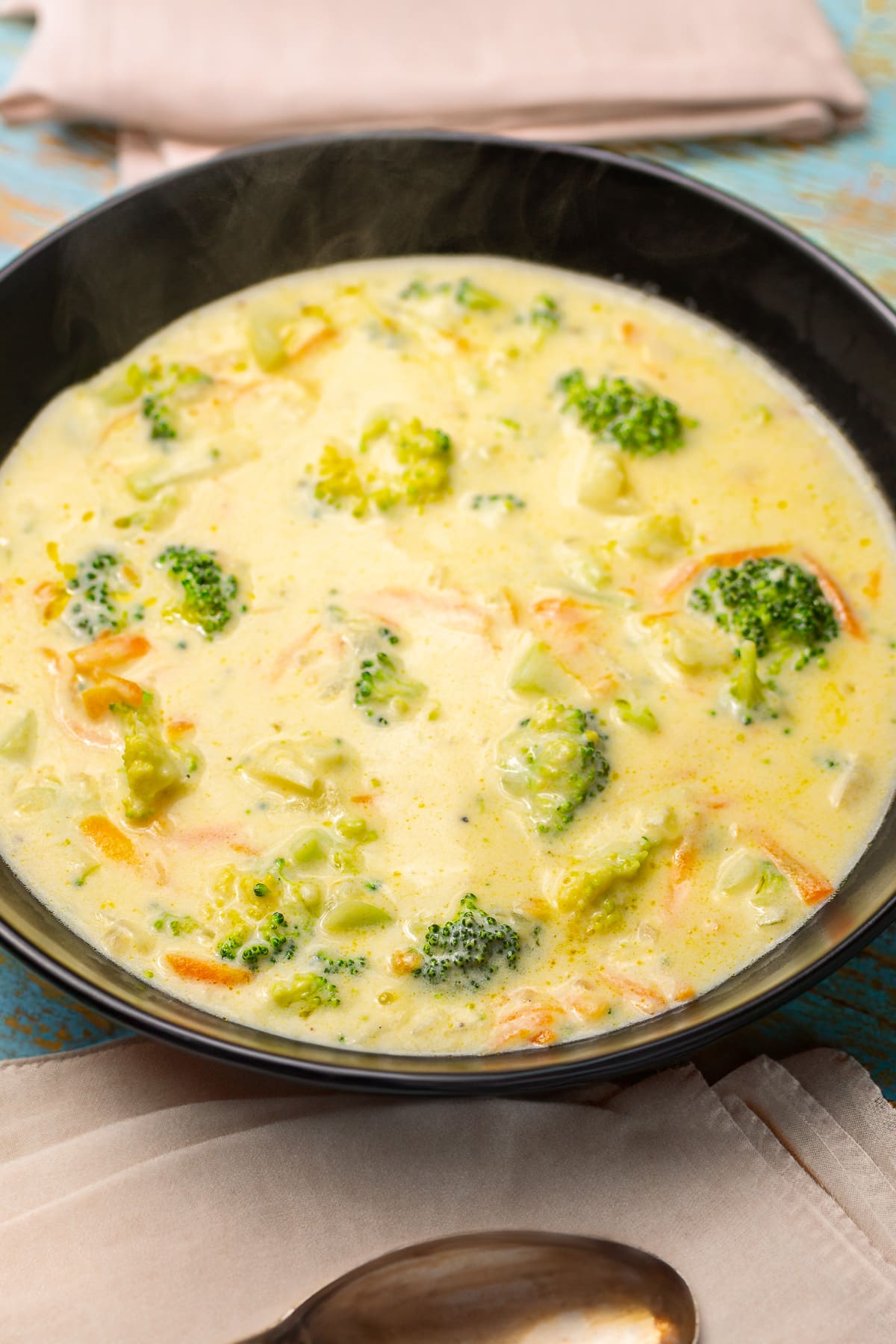 Creamy broccoli cheese soup with carrots in a black plate.