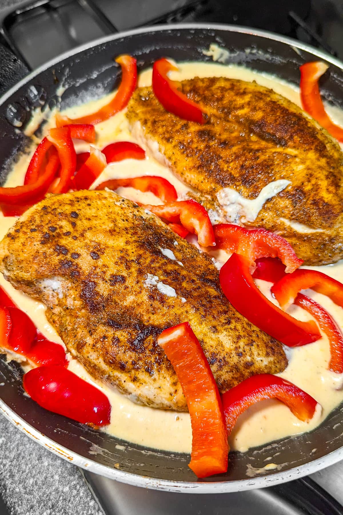 Fried chicken breast in a creamy sauce with bell pepper slices.