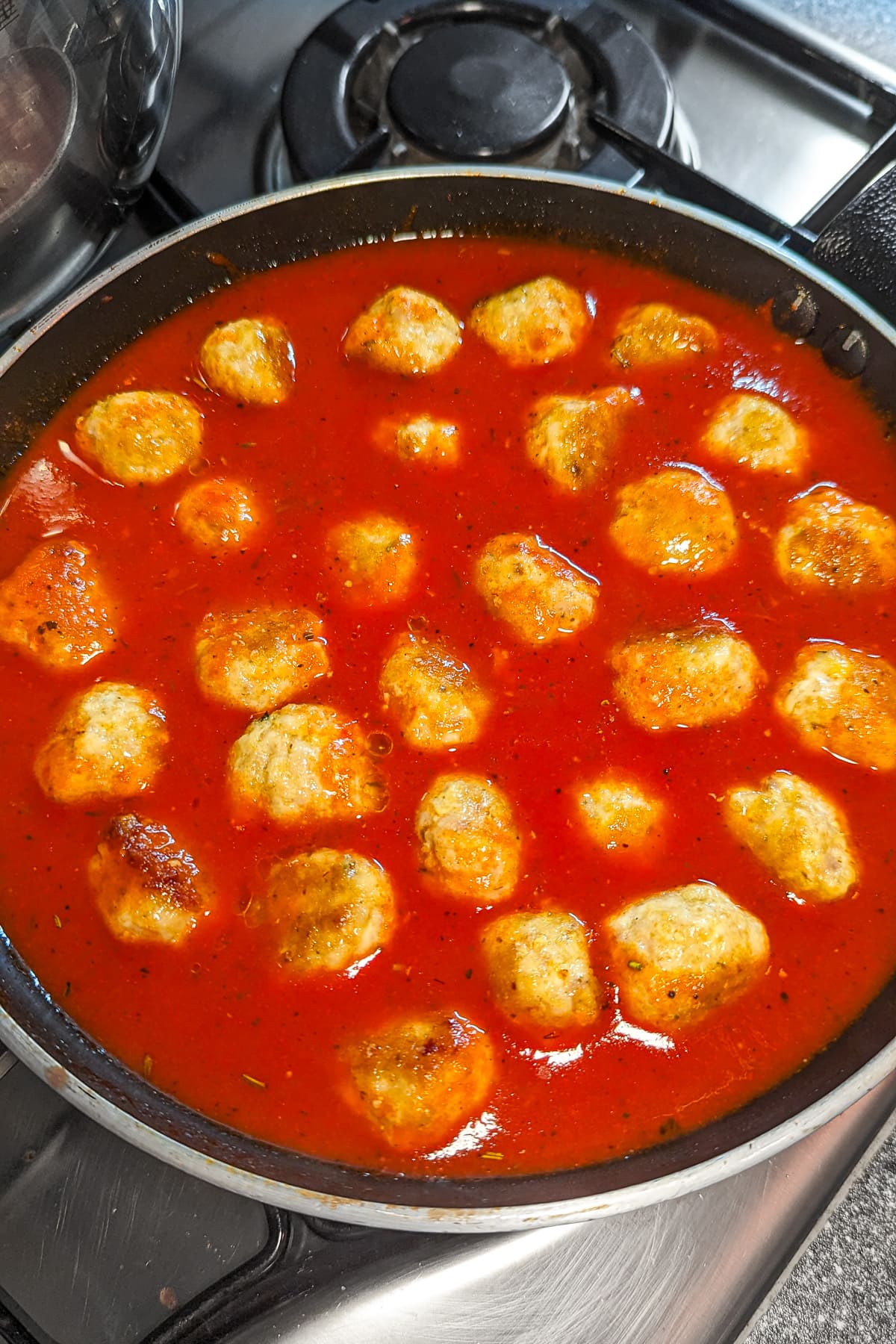 Skillet pan with chicken meatballs in tomato sauce.