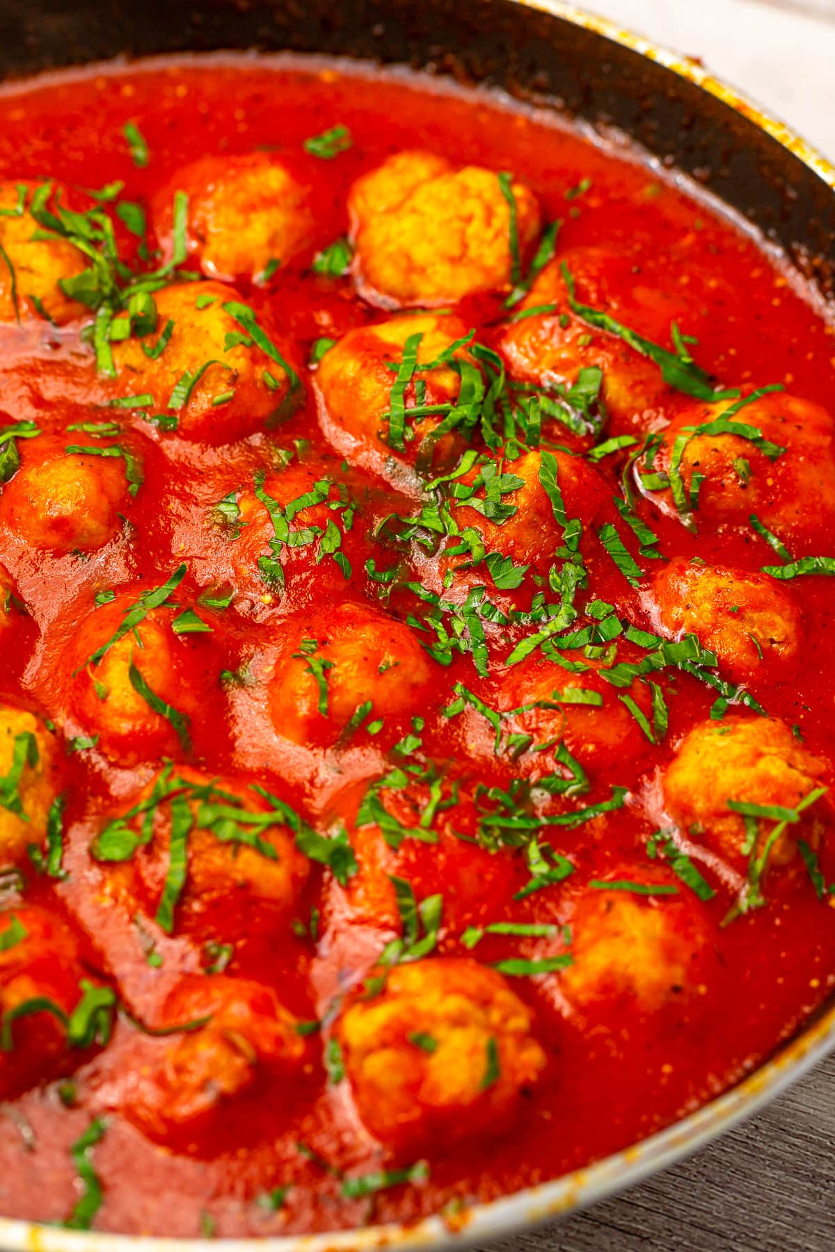 Skillet pan with chicken meatballs in tomato sauce.