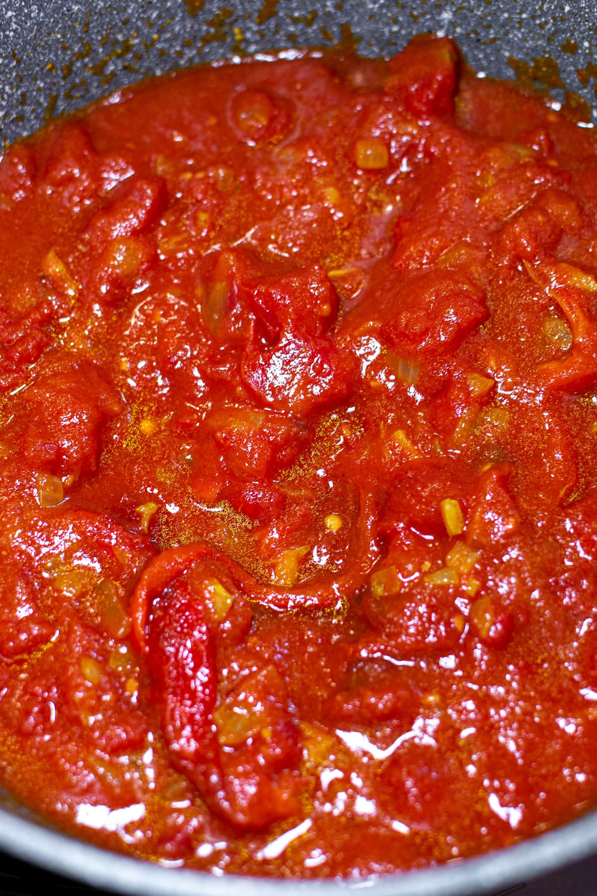 Tomato sauce with bell peppers in a gray pan.