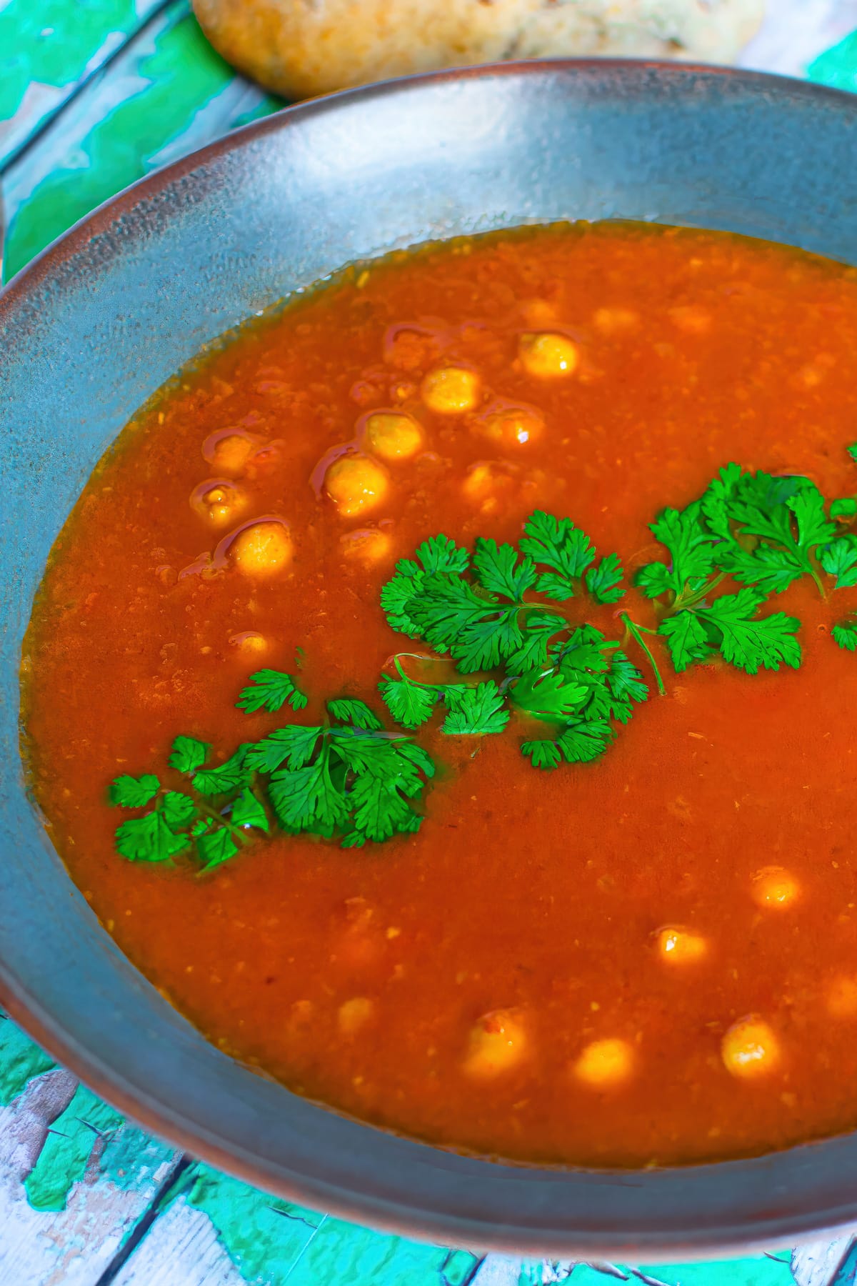 Close up view of chickpea soup with tomatoes and bell peppers.