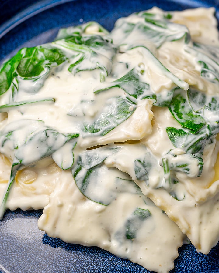 Creamy spinach and cheese ravioli in an elegant blue plate.