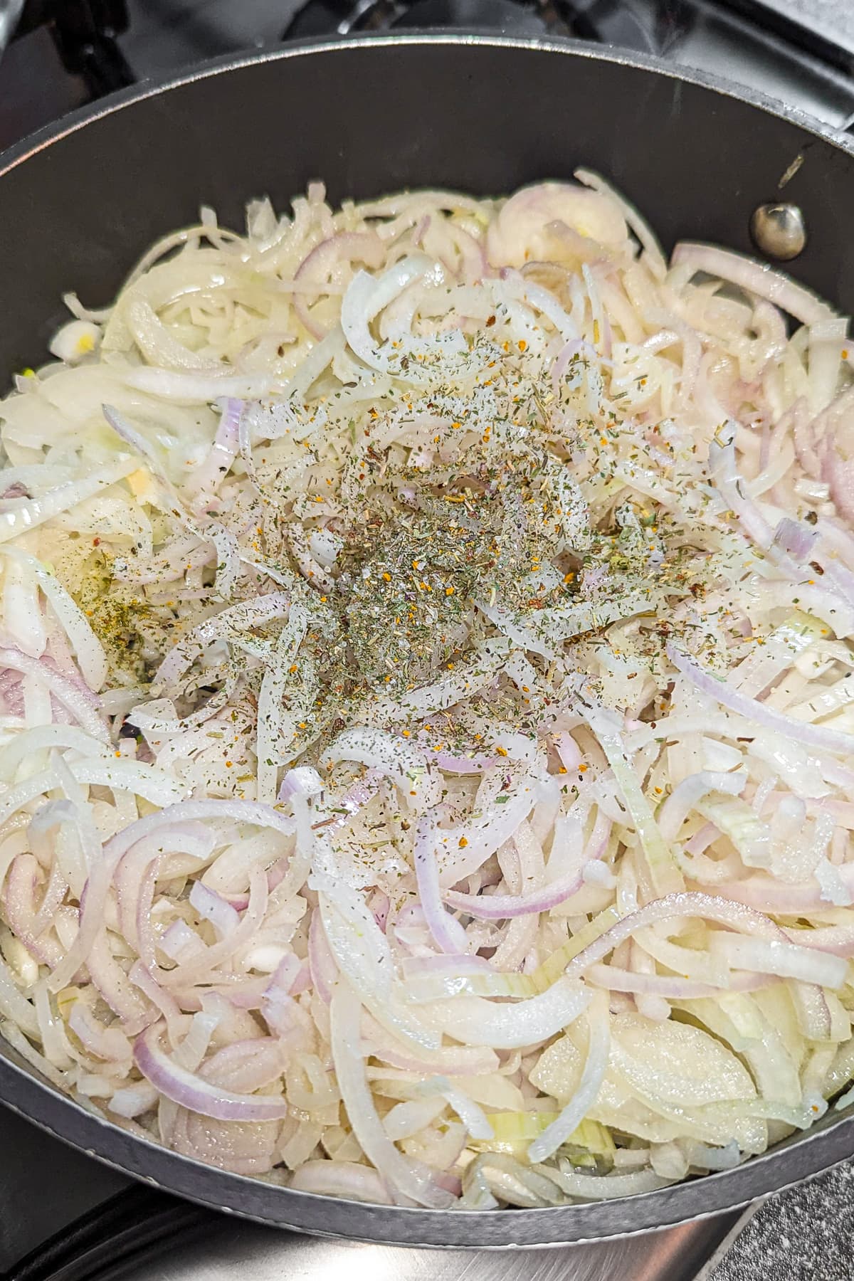 Frying pan with chopped onions with aromatic herbs.