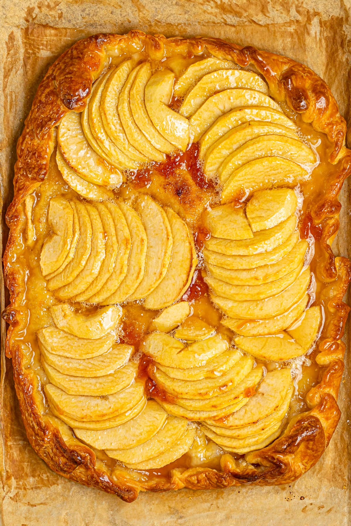 Freshly baked apple tart in a tray, golden crust with beautifully arranged baked apple slices.