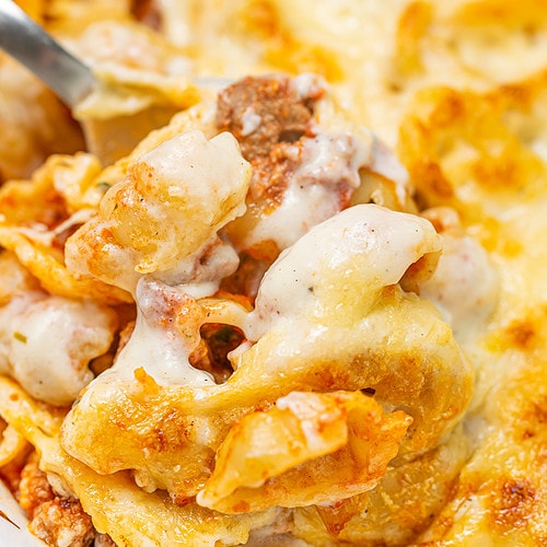 Close-up of baked bolognese pasta with cheese, showing texture and layers.