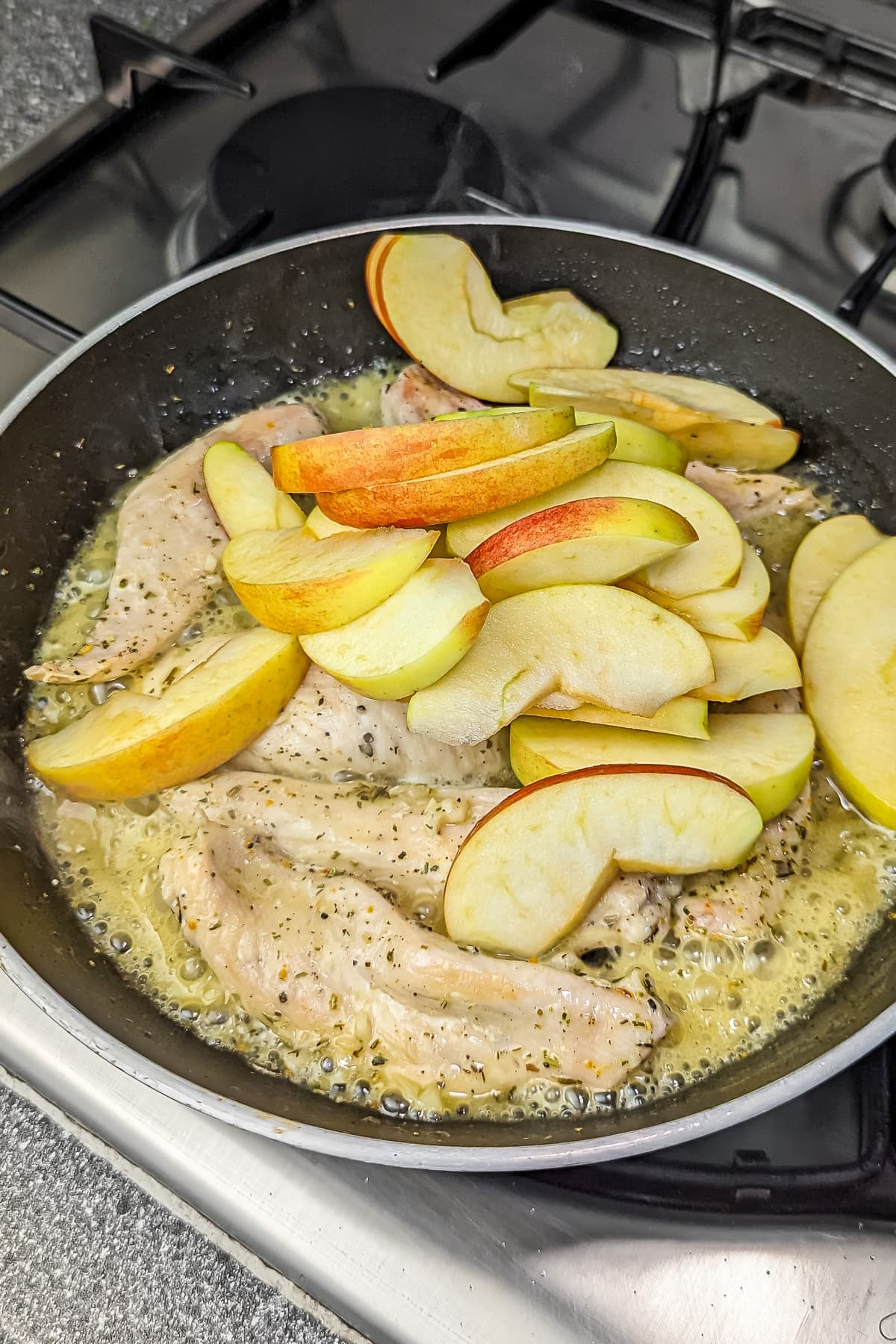 Sliced apples added to the skillet with the chicken and cooking liquids.