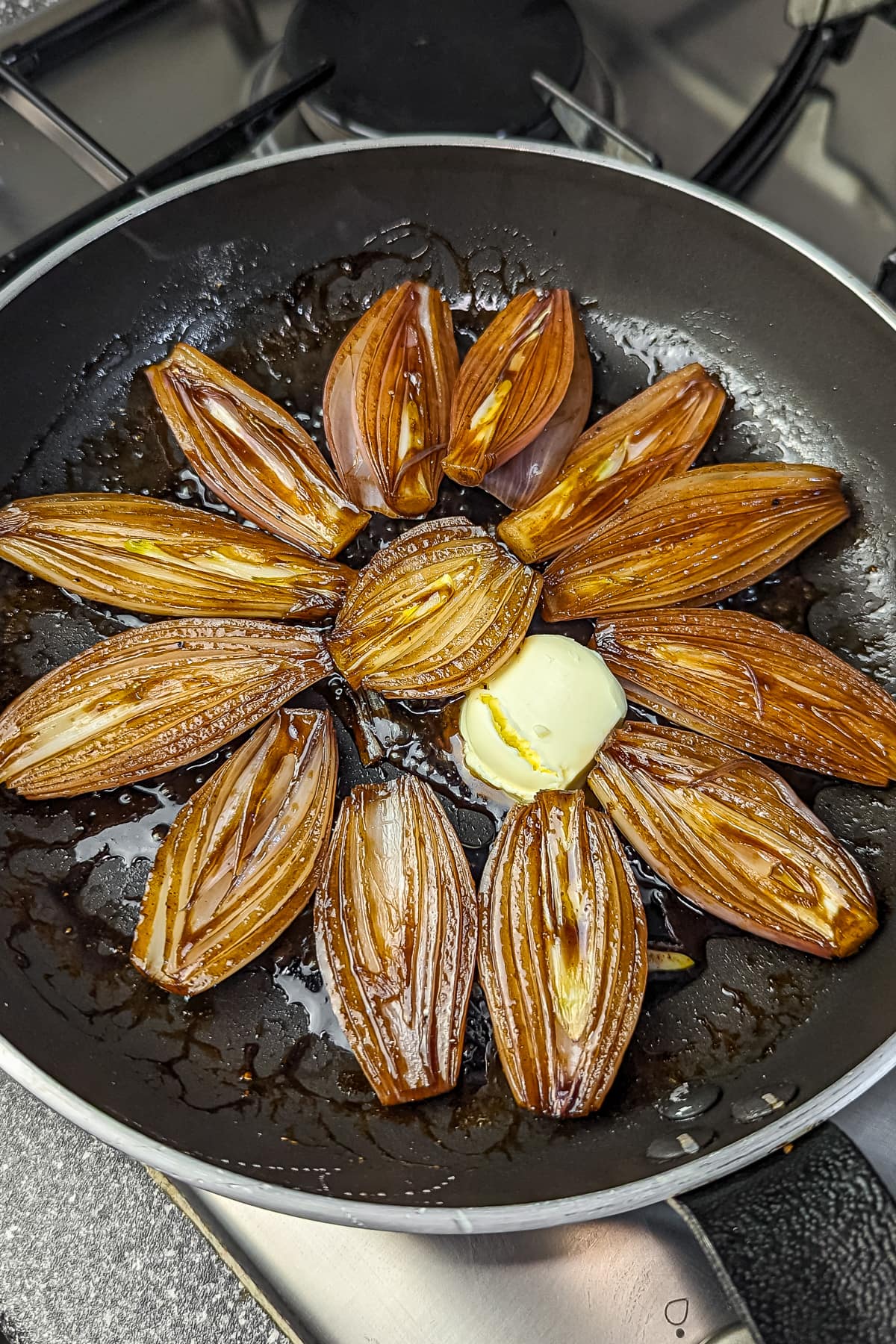 Caramelizing shallots with balsamic glaze and a pat of butter in a skillet.
