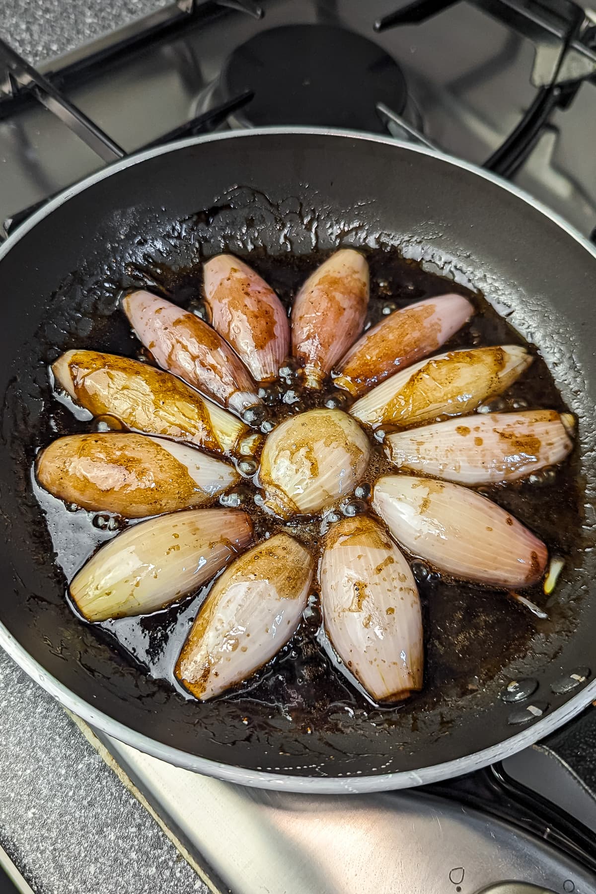 "Cooked shallots glazed with balsamic in a skillet, ready for tart assembly.