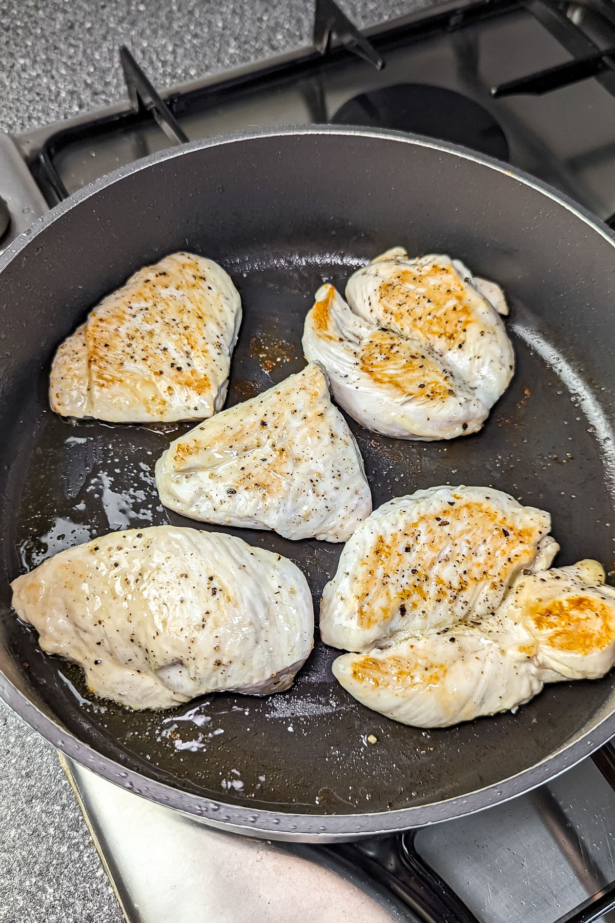 Sautéing chicken breasts in a non-stick pan over medium heat until golden brown, ready for mushroom sauce