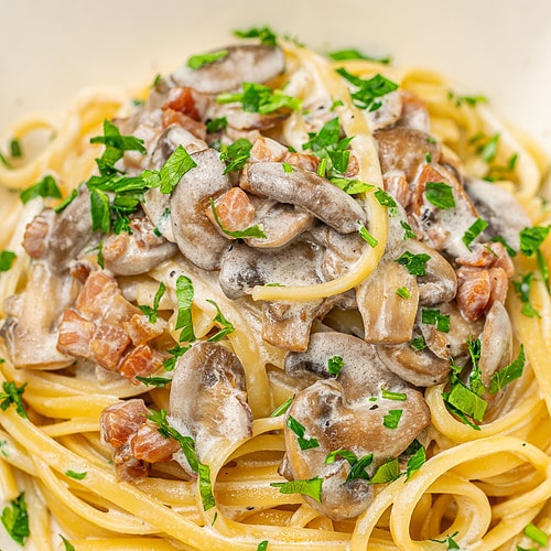 A close-up of creamy mushroom pasta in the pan, garnished with fresh parsley, ready to serve.