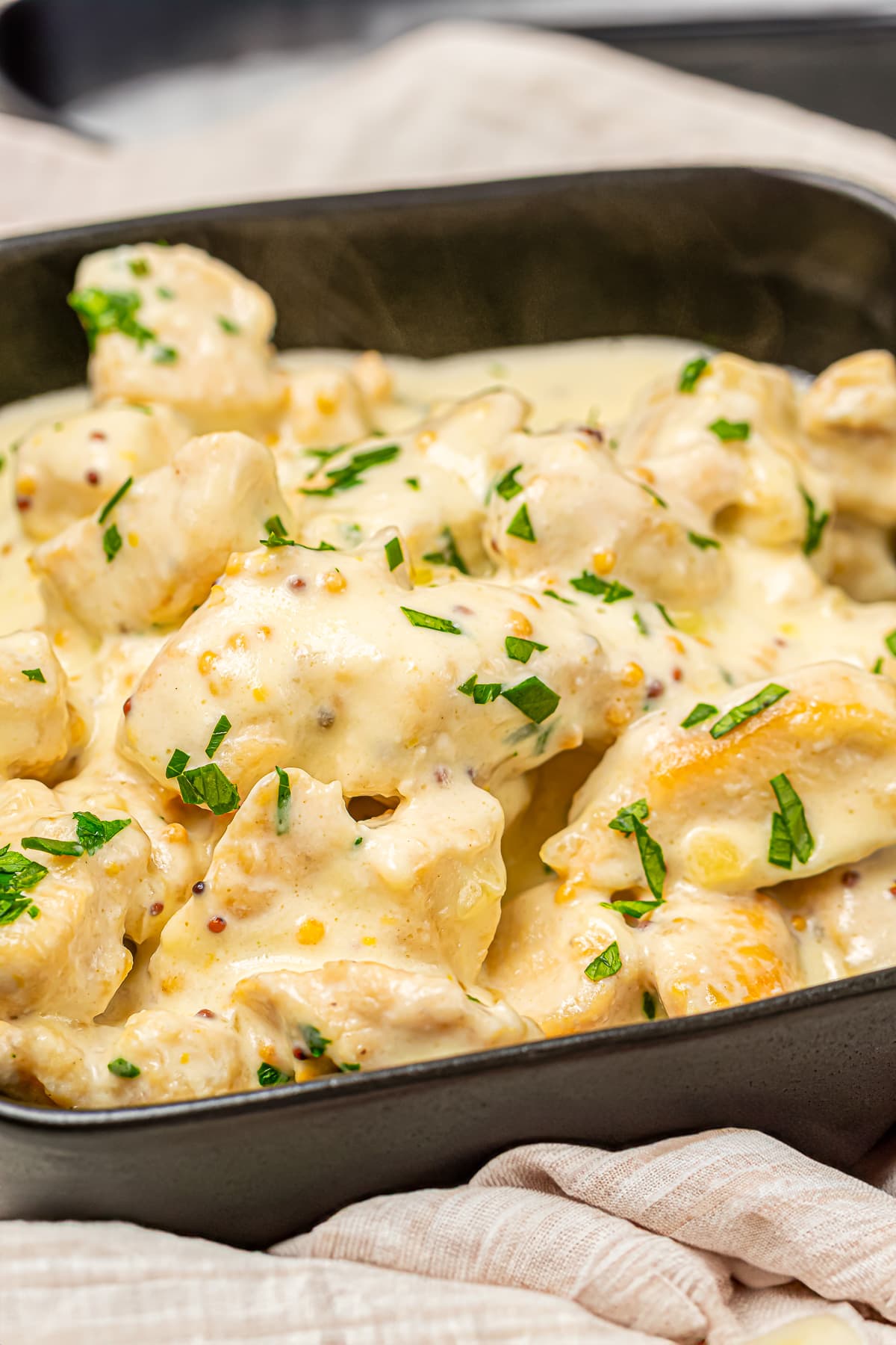 Honey mustard chicken dish presented in a baking tray, ready to be served or further baked, garnished with parsley on top.