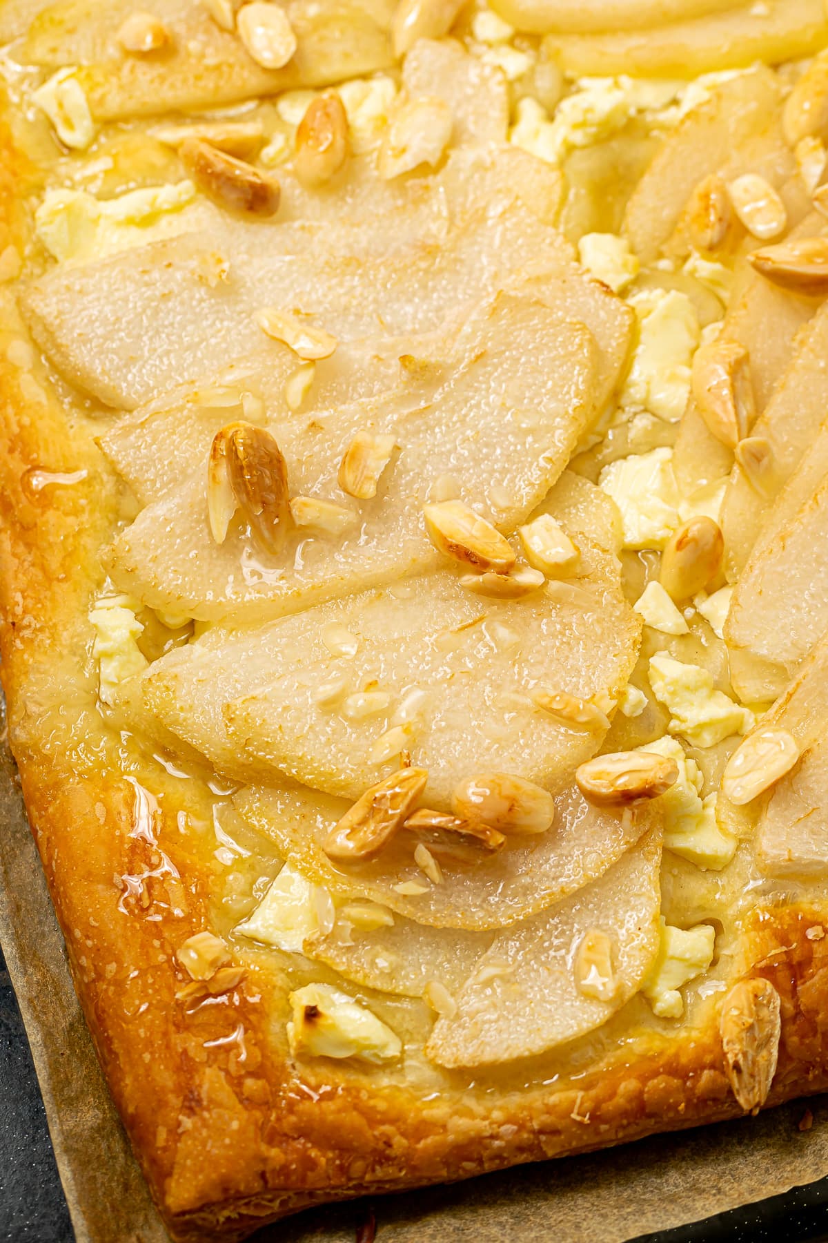Close-up of the pear and feta tart with almonds and honey glaze, highlighting the juicy pear slices.
