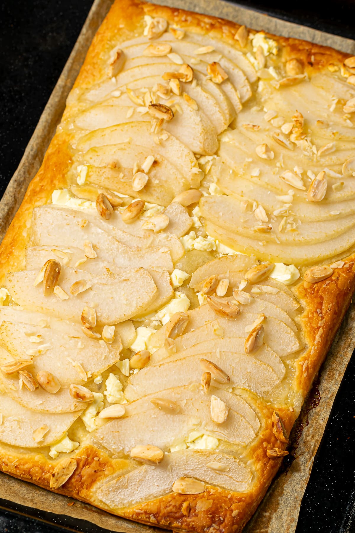 Baked pear and feta tart with almonds, golden brown and crisp, fresh out of the oven.