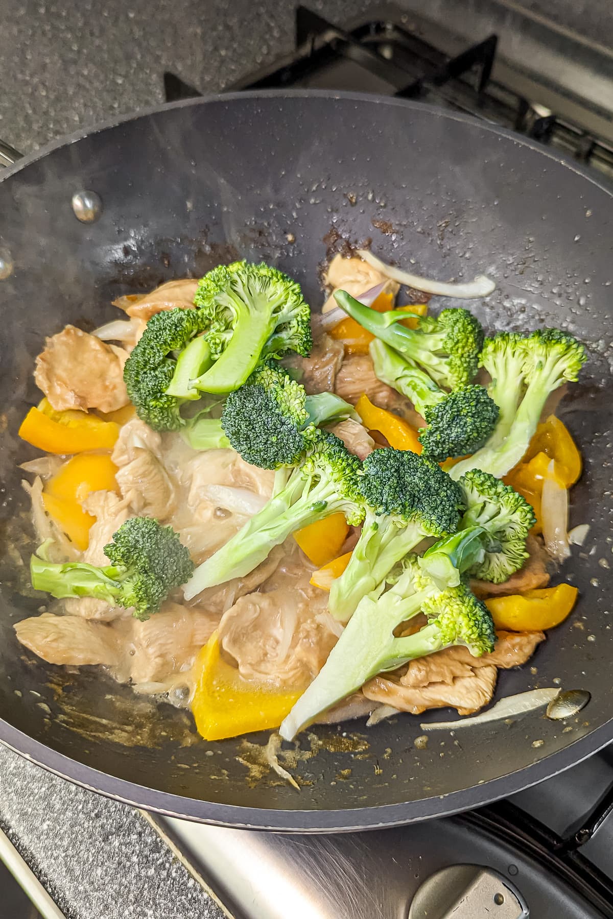 Broccoli florets added to the chicken and bell pepper mix in the pan.
