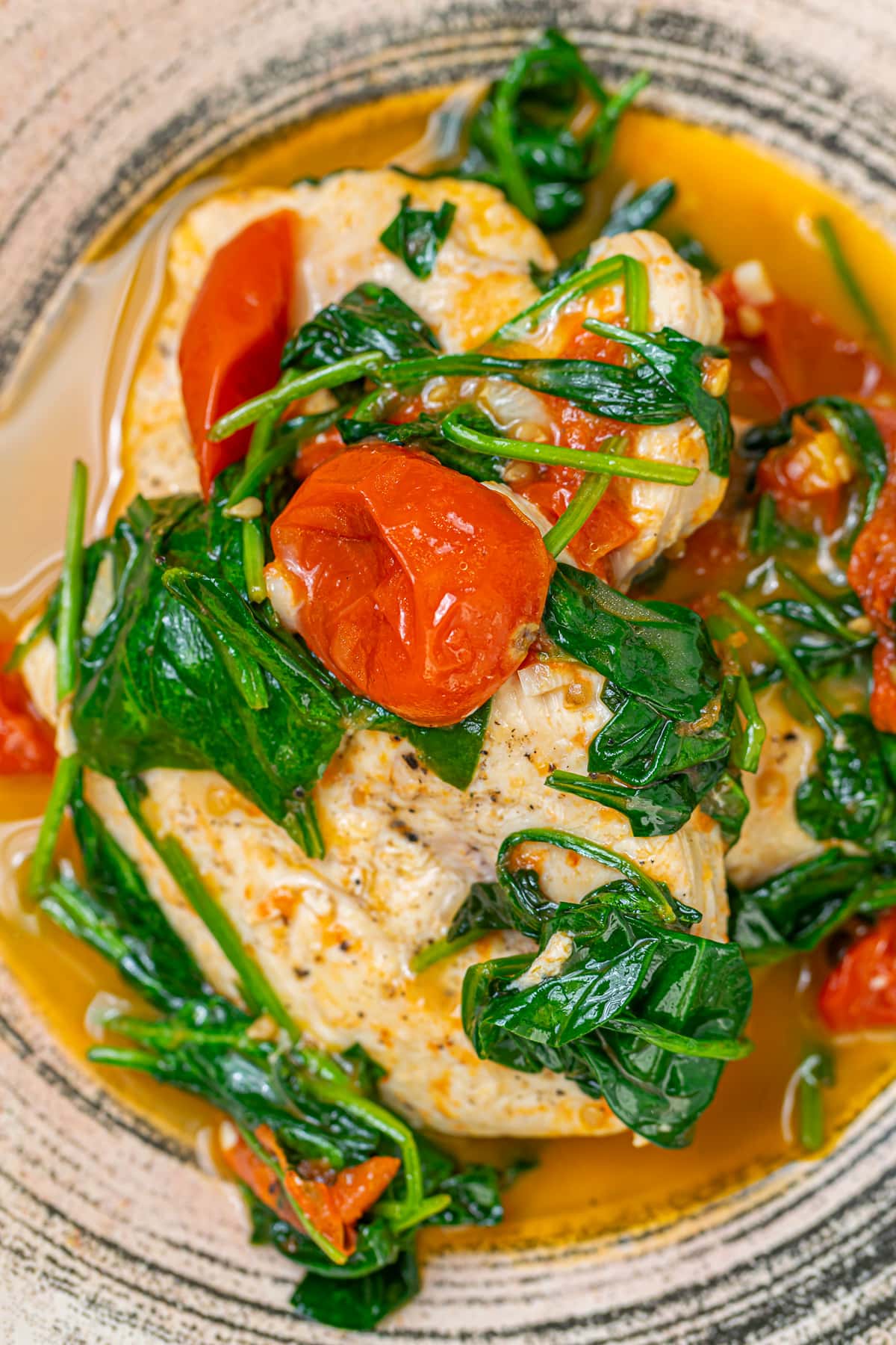 Close-up of the cooked tomato chicken spinach dish with fresh herbs.