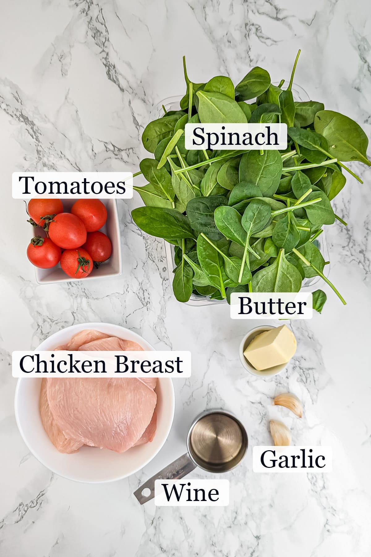 Ingredients for tomato chicken spinach recipe laid out on a marble surface.